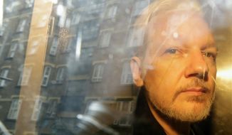 In this file photo dated Wednesday, May 1, 2019, buildings are reflected in the window as WikiLeaks founder Julian Assange is taken from court, where he appeared on charges of jumping British bail seven years ago, in London. (AP Photo/Matt Dunham, File)