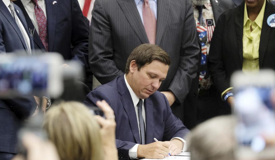 Florida Gov. Ron DeSantis signs the Sanctuary City bill Friday, June 14, 2019 at the Okaloosa County, Fla., Commission Chambers in Shalimar Fla. The bill requires all law enforcement agencies in Florida to cooperate with federal immigration authorities. (Michael Snyder/Northwest Florida Daily News via AP)