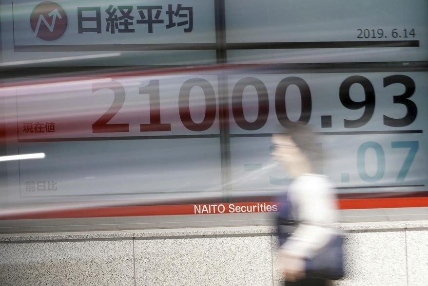A woman walks past an electronic stock board showing Japan's Nikkei 225 index at a securities firm in Tokyo Friday, June 14, 2019. Asian shares were mixed Friday as investors weighed a variety of factors, including suspected attacks on two oil tankers in the strategic Strait of Hormuz and lingering worries about trade conflict between the U.S. and China. (AP Photo/Eugene Hoshiko)