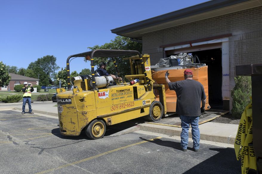 In this Monday, June 10, 2019 photo, workers removed the 12,000 pound open MRI machine from a hole cut into the wall of OSF St. Francis Center for Health - Glen Park in Peoria, Ill. (Leslie Renken/Journal Star via AP)