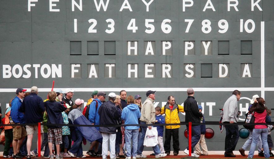 FILE - In this June 21, 2009 file photo, fans tour in front of the scoreboard in Fenway Park in Boston in celebration of Father's Day following a baseball game between the Atlanta Braves and the Boston Red Sox. The U.S. Census Bureau has released a new report showing more than 60% of the 121 million men in the U.S. are fathers. The data in the report released this week of June 15, 2019, comes from 2014 when the bureau for the first time asked both men and women about their fertility histories. The report says just under three-quarters of fathers are married. Almost 13% of dads are divorced and 8% have never been married. (AP Photo/Michael Dwyer)