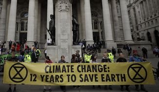 FILE - In this Thursday, April 25, 2019 file photo, Extinction Rebellion climate change protesters hold up a banner near the Bank of England, in the City of London. The environmental activist group Extinction Rebellion has postponed a plan to shut down London&#x27;s Heathrow Airport with drones after it was criticized by politicians and police. The anti-climate change group said Sunday, June 16 it would &amp;quot;not be carrying out any actions at Heathrow Airport in June or July.&amp;quot; (AP Photo/Matt Dunham, file)