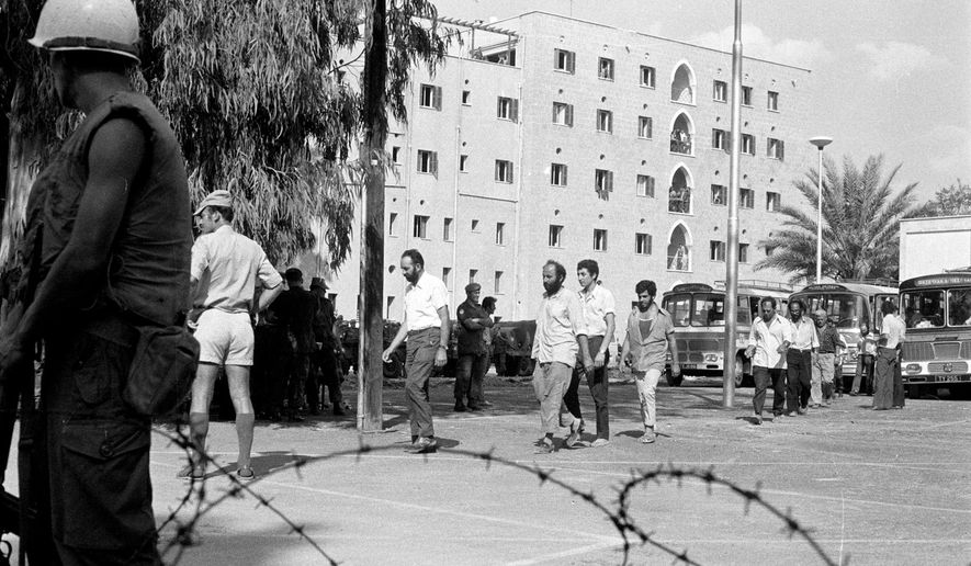 This Sept. 19, 1974, photo provided from the Cyprus&#x27; press and informations office shows the Ledra Palace Hotel in the background during the exchange captive soldiers and civilians between Turkish and Cypriots after the 1974 Turkish invasion, in the divided capital Nicosia, Cyprus. This grand hotel still manages to hold onto a flicker of its old majesty despite the mortal shell craters and bullet holes scarring its sandstone facade. Amid war in the summer of 1974 that cleaved Cyprus along ethnic lines, United Nations peacekeepers took over the Ledra Palace Hotel and instantly turned it into an emblem of the east Mediterranean island nation&#x27;s division. (Press and informations Office, via AP)
