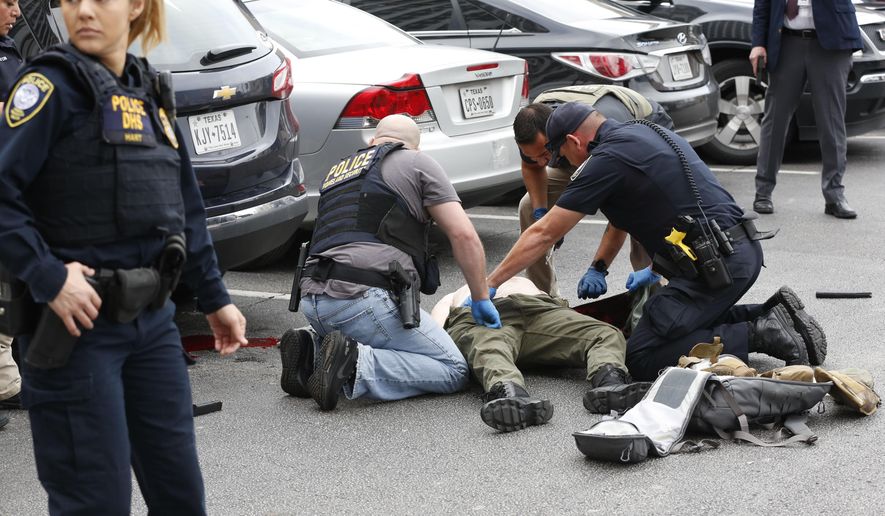Law enforcement officers attend to an injured shooter in a parking lot after he fired shots at the Earle Cabell Federal Building in downtown Dallas, Monday, June 17, 2019. (Tom Fox/The Dallas Morning News)