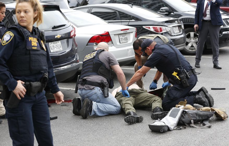 Law enforcement officers attend to an injured shooter in a parking lot after he fired shots at the Earle Cabell Federal Building in downtown Dallas, Monday, June 17, 2019. (Tom Fox/The Dallas Morning News)