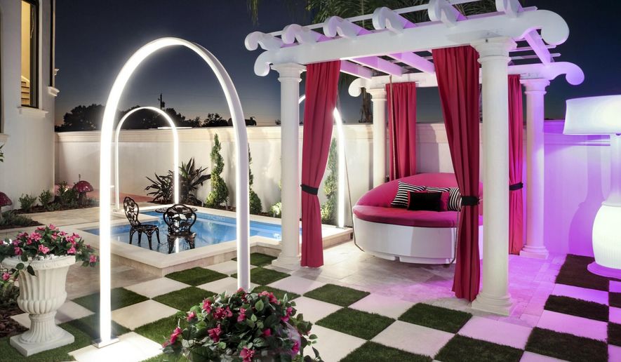 This 2019 photo provided by Ryan Hughes of Ryan Hughes Design Build shows an outdoor space at a home in Florida. Tampa-based designer Hughes for this project took inspiration from the homeowner's daughter's love of Alice in Wonderland to create a playful, over-the-top outdoor space complete with unique lighting effects, a hanging bed and oversized checkerboard. (Joe Traina/Ryan Hughes via AP)
