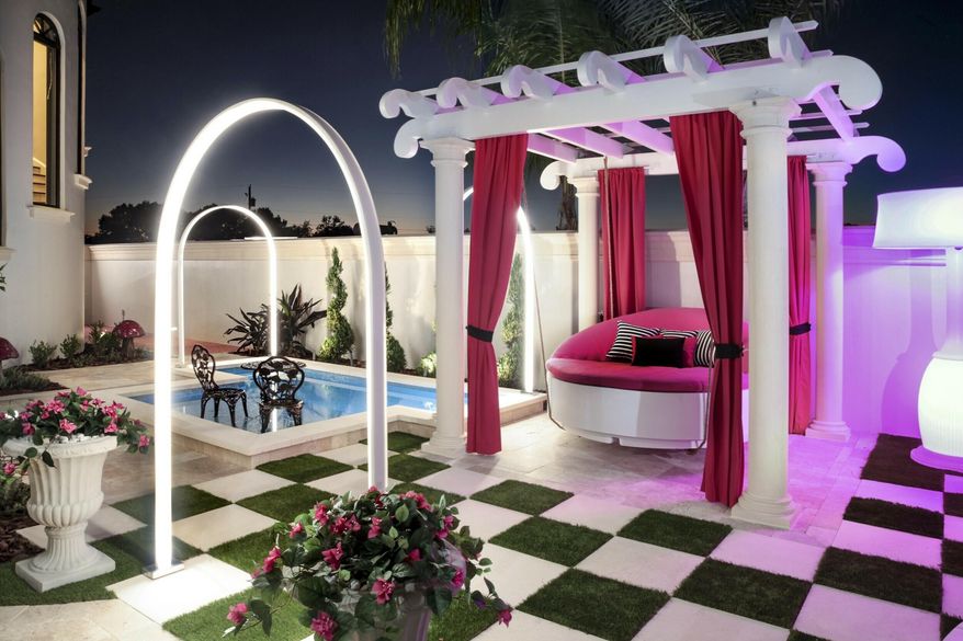 This 2019 photo provided by Ryan Hughes of Ryan Hughes Design Build shows an outdoor space at a home in Florida. Tampa-based designer Hughes for this project took inspiration from the homeowner's daughter's love of Alice in Wonderland to create a playful, over-the-top outdoor space complete with unique lighting effects, a hanging bed and oversized checkerboard. (Joe Traina/Ryan Hughes via AP)