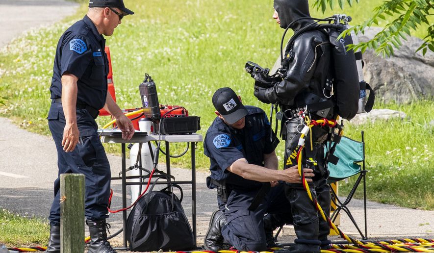 Police search the Kalamazoo River near Verburg Park, Tuesday, June 18, 2019, after finding the bodies of a mother and child inside a submerged vehicle, in Kalamazoo, Mich. Police believe a second child, who is missing, may also have been inside the vehicle when it entered the water late Monday evening. (Joel Bissell/Kalamazoo Gazette via AP)