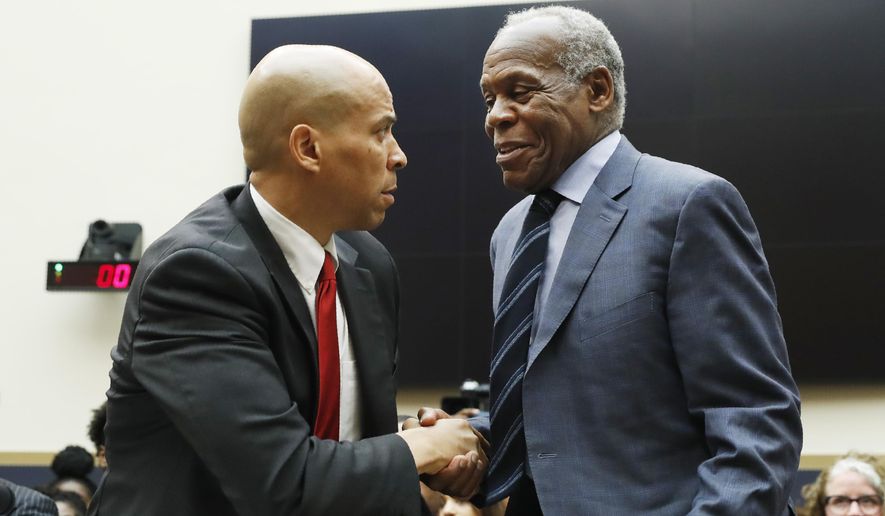 Democratic Presidential candidate Sen. Cory Booker, D-NJ, left, greets actor Danny Glover, before they testify about reparations for the descendants of slaves, during a hearing before the House Judiciary Subcommittee on the Constitution, Civil Rights and Civil Liberties, at the Capitol in Washington, Wednesday, June 19, 2019. (AP Photo/Pablo Martinez Monsivais)
