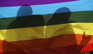 In this Friday, May 17, 2019, file photo, LGBT refugees living in Kenya stand behind a rainbow flag as they protest against their treatment by authorities, outside an office of the U.N. refugee agency UNHCR in Nairobi, Kenya. (AP Photo/Ben Curtis, File)