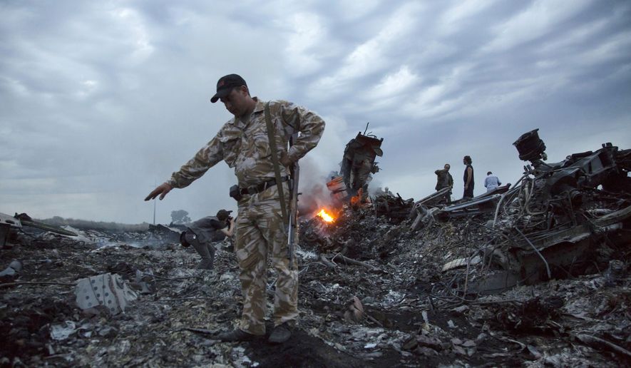 In this July 17, 2014, file photo, people walk amongst the debris at the crash site of a passenger plane near the village of Grabovo, Ukraine. An international team of investigators building a criminal case against those responsible in the downing of Malaysia Airlines Flight 17 is set to announce progress in the probe on Wednesday, June 19, 2019, nearly five years after the plane was blown out of the sky above conflict-torn eastern Ukraine. (AP Photo/Dmitry Lovetsky, File)