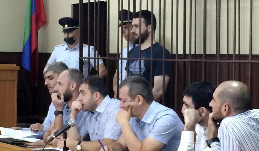 In this photo taken on Sunday, June 16, 2019, Abdulmumin Gadzhiev, the religious affairs editor of the independent weekly Chernovik, stands in a cage in a court room in Makhachkala, the Caspian Sea province of Dagestan, Russia, Sunday, June 16, 2019. Journalists in southern Russia are protesting the arrest of a newspaper editor on charges of terrorism widely seen as trumped up. (Sergei Rasulov, News Team via AP)