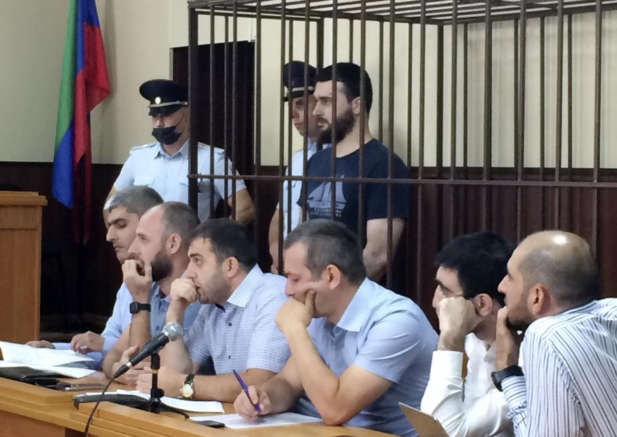 In this photo taken on Sunday, June 16, 2019, Abdulmumin Gadzhiev, the religious affairs editor of the independent weekly Chernovik, stands in a cage in a court room in Makhachkala, the Caspian Sea province of Dagestan, Russia, Sunday, June 16, 2019. Journalists in southern Russia are protesting the arrest of a newspaper editor on charges of terrorism widely seen as trumped up. (Sergei Rasulov, News Team via AP)