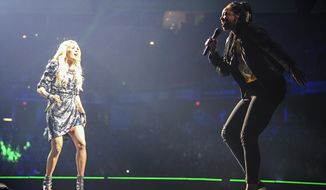In this Sunday, June 16, 2019, photo, Carrie Underwood, left, performs &amp;quot;The Champion&amp;quot; with Indiana Fever&#39;s Erica McCall onstage during Underwood&#39;s concert in Indianapolis. McCall, who said she started rapping in high school and had the nickname Medium E, auditioned for the guest spot at the urgings of team vice president Tamika Catchings. (Jessica Hoffman/Indiana Fever via AP)