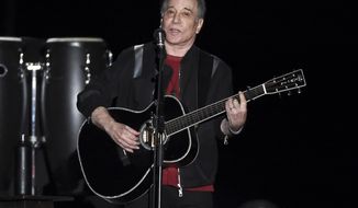 FILE - This Sept. 22, 2018 file photo shows singer-songwriter Paul Simon performing in Flushing Meadows Corona Park during the final stop of his Homeward Bound - The Farewell Tour in New York. Simon was honored by the Poetry Society of America and celebrated by reading a couple of poems and singing a few songs. During a dinner benefit Tuesday night, June 18, 2019, at the New York Botanical Garden, Simon and poetry editor Alice Quinn were praised for their love for language. Quinn is the former poetry editor for The New Yorker and is stepping down as the poetry society’s executive editor. Simon is regarded as among the first composers to bring a consciously literary sensibility to rock music.(Photo by Evan Agostini/Invision/AP, File)