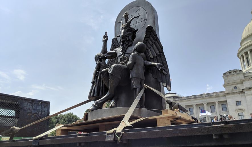 The Satanic Temple unveils its statue of Baphomet, a winged-goat creature, at a rally for the first amendment in Little Rock, Ark., Thursday, Aug. 16, 2018. The Satanic Temple wants to install the statue on Capitol grounds as a symbol for religious freedom after a monument of the Biblical Ten Commandments was installed in 2017. (AP Photo/Hannah Grabenstein)