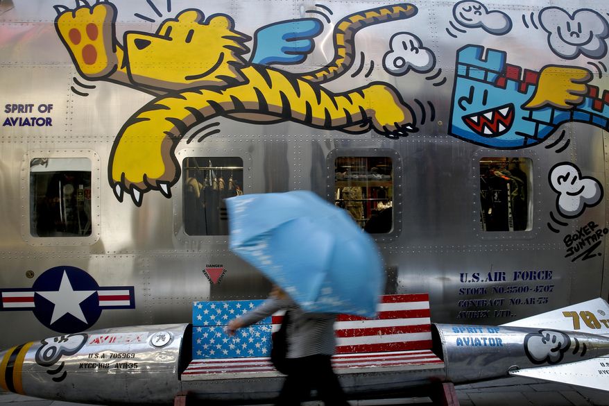 FILE - In this May 13, 2019, file photo, a woman walks by a bench painted with an American flag outside a fashion boutique selling U.S. brand clothing at the capital city's popular shopping mall in Beijing. China's Commerce Ministry said Thursday, June 20, 2019, that officials on both sides are preparing for a meeting of Presidents Donald Trump and Xi Jinping in Osaka, but that threats and tariffs will not resolve trade tensions between the two biggest economies. (AP Photo/Andy Wong, File)