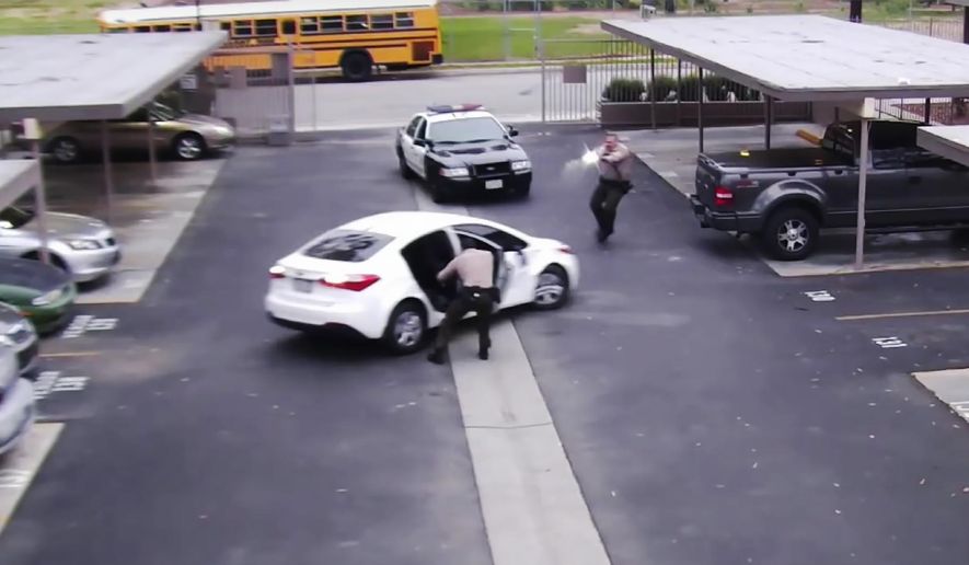 In this June 6, 2019 image from surveillance video provided by the Los Angeles County Sheriff&#39;s Department, a Los Angeles County sheriff deputy opens a rear door of a parked vehicle while a fellow office fires his gun at the car, fatally shooting Ryan Twyman. The video shows the reversing car&#39;s door striking the deputy before he and the other deputy open fire on the vehicle.  The family of Twyman, who was unarmed during the incident, filed a claim for damages against Los Angeles County. (Los Angeles County Sheriff Department via AP)