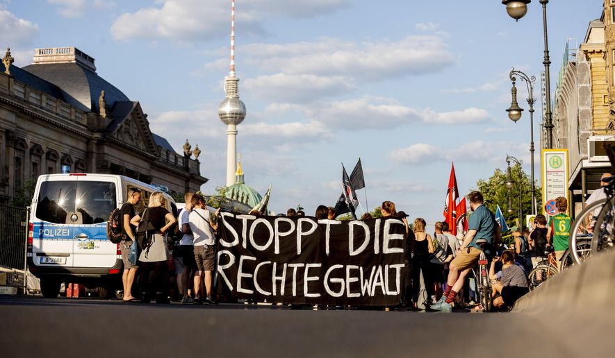 People attend a protest ralley in Berlin, Germany, Tuesday, June 18, 2019 against far right violence. German police are investigating a series of threats sent to officials and institutions days after the arrest of a far-right extremist on suspicion of killing a pro-migrant politician. Slogan reads 'Stop Far Right Violence' (Christoph Soeder/dpa via AP)