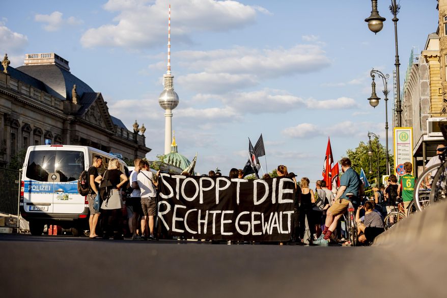 People attend a protest ralley in Berlin, Germany, Tuesday, June 18, 2019 against far right violence. German police are investigating a series of threats sent to officials and institutions days after the arrest of a far-right extremist on suspicion of killing a pro-migrant politician. Slogan reads 'Stop Far Right Violence' (Christoph Soeder/dpa via AP)