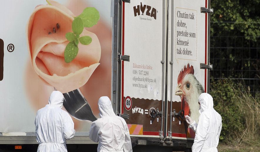 FILE - In this Thursday, Aug. 27, 2015 file photo, investigators stand near an abandoned truck on the shoulder of Highway A4 near Parndorf, Austria, south of Vienna. A Hungarian court has extended the prison sentences of four human traffickers convicted last year for their roles in a 2015 in which 71 migrants suffocated to death in the back of a refrigerated truck found on a highway in Austria. (AP Photo/Ronald Zak, file)