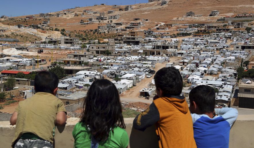 In this Sunday, June 16, 2019 photo, Lebanese children look from the rooftop of their home at a Syrian camp in the eastern Lebanese border town of Arsal, Lebanon. Authorities in Lebanon are waging their most aggressive campaign yet against Syrian refugees, making heated calls for them to go back to their country and taking action to ensure they can’t put down roots. They are shutting down shops where Syrians work without permits and ordering the demolition of anything in their squalid camps that could be a permanent home. (AP Photo/Bilal Hussein)