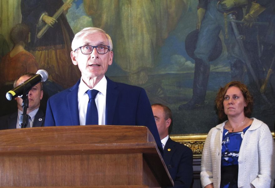 Wisconsin Gov. Tony Evers, surrounded by Democratic lawmakers and members of his Cabinet at a Capitol news conference, is urging Republicans who control the Legislature to pass a state budget that includes Medicaid expansion and more money for schools on Thursday, June 20, 2019, in Madison, Wis. The Legislature is scheduled to debate the budget next week. (AP Photo/Scott Bauer)