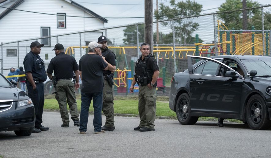 In this Thursday, June 20, 2019 photo, Detroit police investigate a shooting on the 2400 block of Honorah in Detroit. Detroit police say a father fatally shot a young man who allegedly shot his 15-year-old son in the face while trying to rob the boy during the sale of a video game.(David Guralnick/Detroit News via AP)