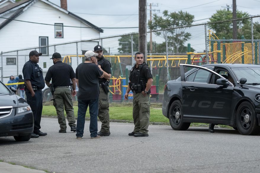 In this Thursday, June 20, 2019 photo, Detroit police investigate a shooting on the 2400 block of Honorah in Detroit. Detroit police say a father fatally shot a young man who allegedly shot his 15-year-old son in the face while trying to rob the boy during the sale of a video game.(David Guralnick/Detroit News via AP)