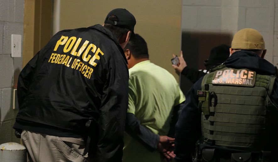 In this Oct. 22, 2018, file photo U.S. Immigration and Customs Enforcement agents escort a target to lockup during a raid in Richmond, Va. On Friday, Nov. 15, 2019, immigration officials tied a third murder arrest in two months to sanctuary city policies in the Seattle, Washington, area, saying an illegal immigrant who was twice shielded from deportation by King County slew a man &quot;as he lay asleep in his own home.&quot;  (AP Photo/Steve Helber, File)
