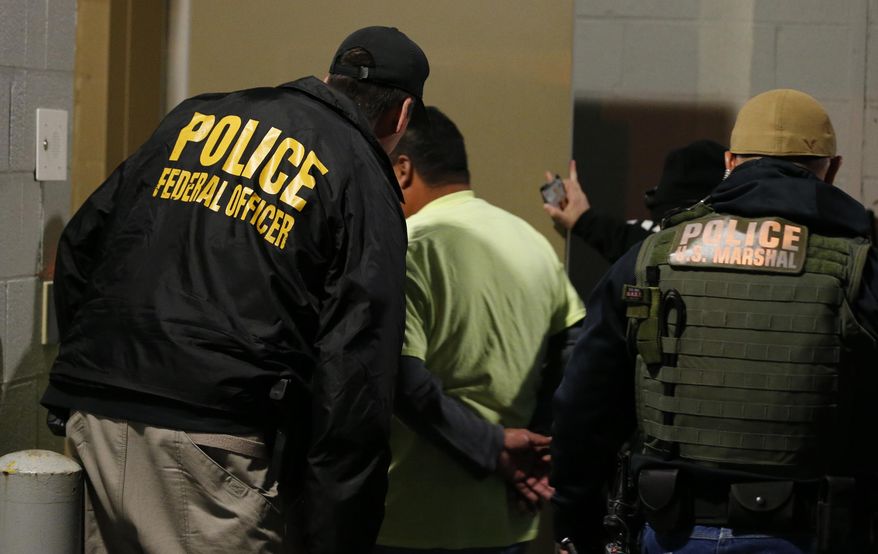 In this Oct. 22, 2018, file photo U.S. Immigration and Customs Enforcement agents escort a target to lockup during a raid in Richmond, Va. On Friday, Nov. 15, 2019, immigration officials tied a third murder arrest in two months to sanctuary city policies in the Seattle, Washington, area, saying an illegal immigrant who was twice shielded from deportation by King County slew a man &quot;as he lay asleep in his own home.&quot;  (AP Photo/Steve Helber, File)
