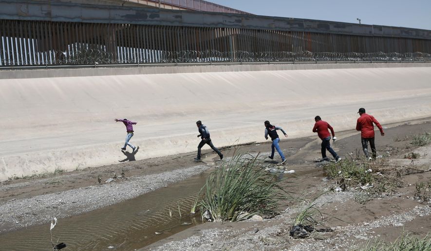 In this June 15, 2019, photo, migrants cross the Rio Bravo illegally to surrender to the American authorities, on the U.S.-Mexico border between Ciudad Juarez and El Paso. (Associated Press) **FILE**