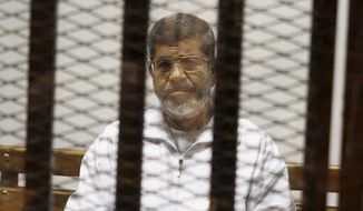 FILE - In this May 8, 2014 file photo, Egypt&#39;s ousted Islamist President Mohammed Morsi sits in a defendant cage in the Police Academy courthouse in Cairo, Egypt.  Morsi’s collapse and death in a Cairo courtroom on June 17, 2019,  was a brief rallying point for the Muslim Brotherhood whose influence waned dramatically in the Middle East since the 2013 military coup in Egypt which had widespread public support at the time. The long-running enmity between the Brotherhood and most Sunni-led governments highlights the deep divisions among Sunni Muslims. It adds a further complication to the volatile region, where the split between Sunnis and Shiite Muslims has created rival camps.  (AP Photo/Tarek el-Gabbas, File)