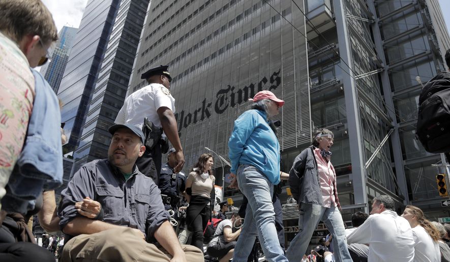 Activists sit on an intersection as others are taken into custody by New York Police officers during a climate change rally outside of the New York Times building, Saturday, June 22, 2019, in New York. Activists blocked traffic along 8th Avenue during a sit-in to demand coverage of climate change by the newspaper. (AP Photo/Julio Cortez)