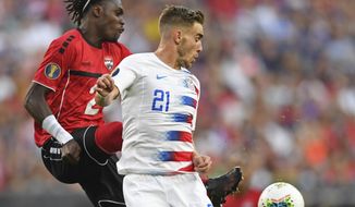 U.S. forward Tyler Boyd plays the ball against Trinidad and Tobago defender Aubrey David during the first half of a CONCACAF Gold Cup soccer match Saturday, June 22, 2019, in Cleveland. (AP Photo/David Dermer)