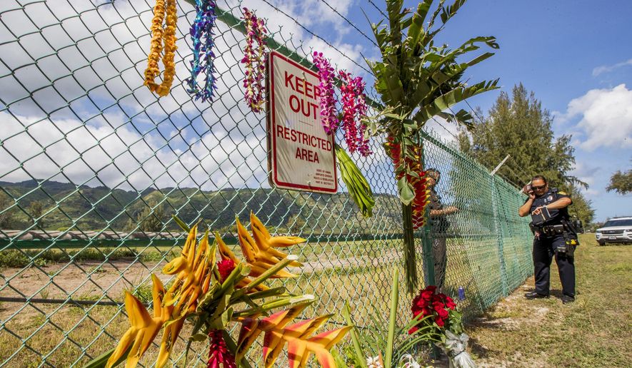 A memorial is seen at the site where a Beechcraft King Air twin-engine plane crashed Friday evening killing multiple people near the chain link fence surrounding Dillingham Airfield in Mokuleia, Hawaii. Police and sheriffs patrol the area. No one aboard survived the skydiving plane crash. The flight was operated by the Oahu Parachute Center skydiving company. (Dennis Oda/Honolulu Star-Advertiser via AP)
