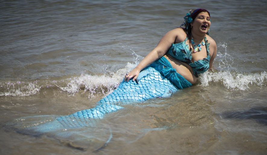 A parade attendee in costume refreshes herself at the sea during the 37th annual Mermaid Parade at Coney Island, Saturday, June 22, 2019 in New York. (AP Photo/Eduardo Munoz Alvarez)