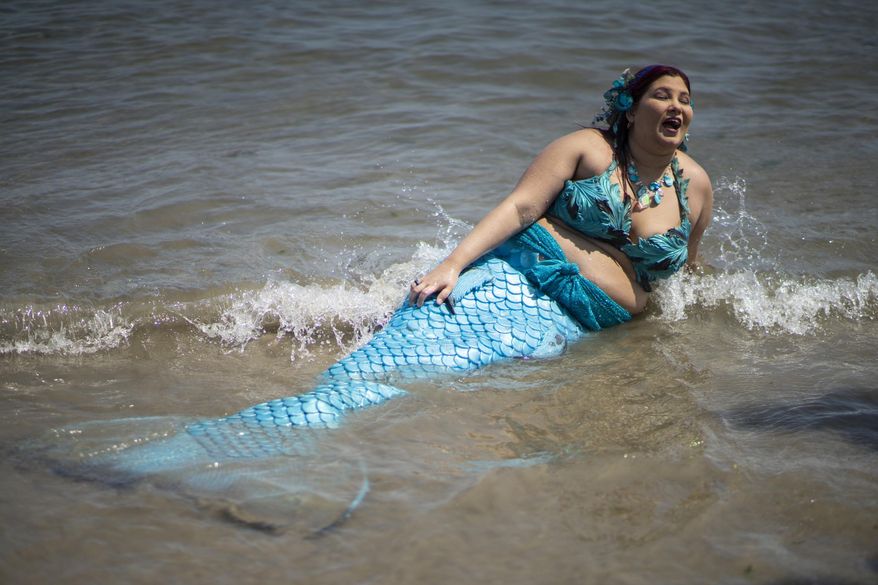 A parade attendee in costume refreshes herself at the sea during the 37th annual Mermaid Parade at Coney Island, Saturday, June 22, 2019 in New York. (AP Photo/Eduardo Munoz Alvarez)