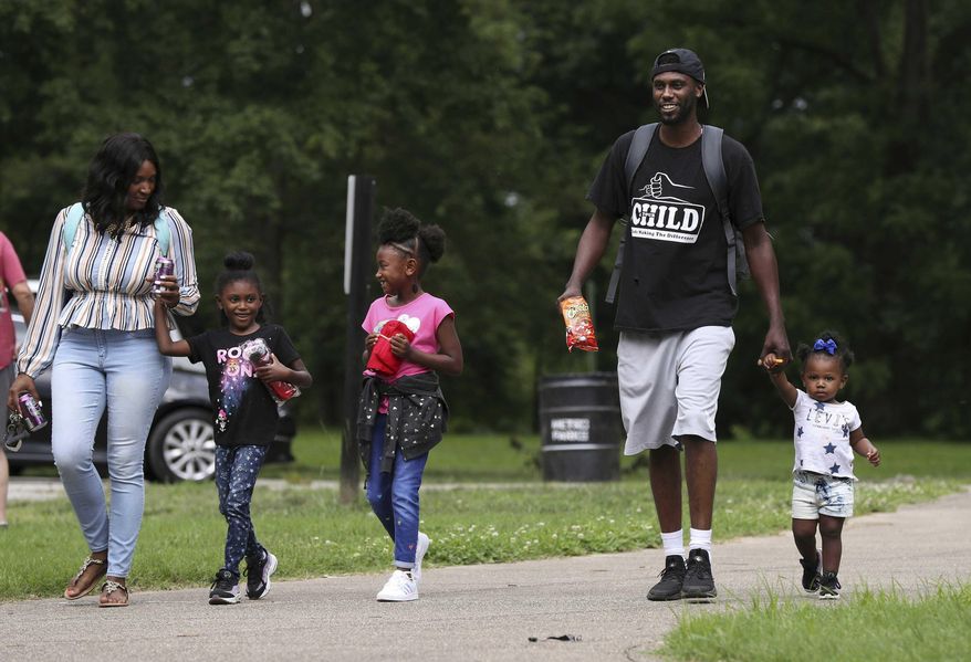 This photo taken June 12, 2019, shows Detrick Ellery walking with his daughter Derian Ellery, 1, right, while his other daughters Demi Ellery, 6, center, and Demiah Ellery, 6, joined them on their way to the playground at Shawnee Park in Louisville, Ky. Demiah and Derian's mom Latasha Norfleet was at left. Detrick is enrolled in the 4 Your Child parenting skills program. (Sam Upshaw Jr./Courier Journal via AP)