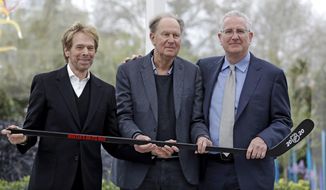 FILE - In this April 11, 2018, file photo, part-owners, from left to right,  Jerry Bruckheimer and David Bonderman pose with Tod Leiweke and a hockey stick during a news conference naming Leiweke as the president and CEO for a prospective NHL expansion team in Seattle. More than six months after the NHL announced its 32nd franchise, what&#39;s happening in Seattle remains a curiosity in the hockey community. With the draft in Vancouver and Seattle team president and CEO Leiweke and part-owner Bruckheimer hanging out for the weekend, it amplified the questions about what is to come next for the yet-to-be-named franchise a couple hours to the south. (AP Photo/Elaine Thompson, File)