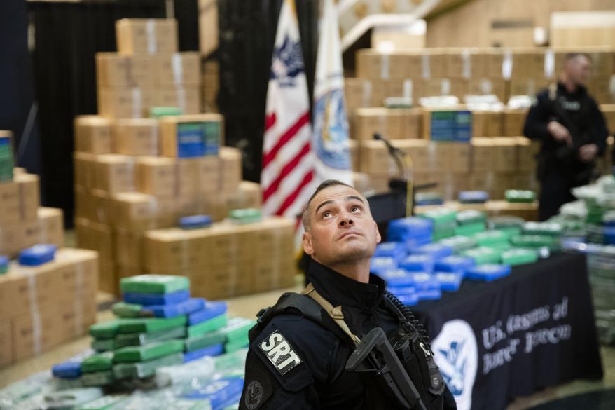 FILE - In a Friday, June 21, 2019, file photo, an officer stands guard over a fraction of the cocaine seized from a ship at a Philadelphia port that was displayed at a news conference at the U.S. Custom House in Philadelphia. Detention hearings are scheduled Monday, June 24, 2019, in Philadelphia for six crew members of the Swiss-owned container ship following the seizure of more than 35,000 pounds, or more than 15,800 kilograms, of cocaine. (AP Photo/Matt Rourke, File)