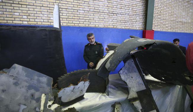 Head of the Revolutionary Guard&#x27;s aerospace division Gen. Amir Ali Hajizadeh looks at debris from what the division describes as the U.S. drone which was shot down on Thursday, in Tehran, Iran, Friday, June 21, 2019. (Meghdad Madadi/Tasnim News Agency/via AP) ** FILE **