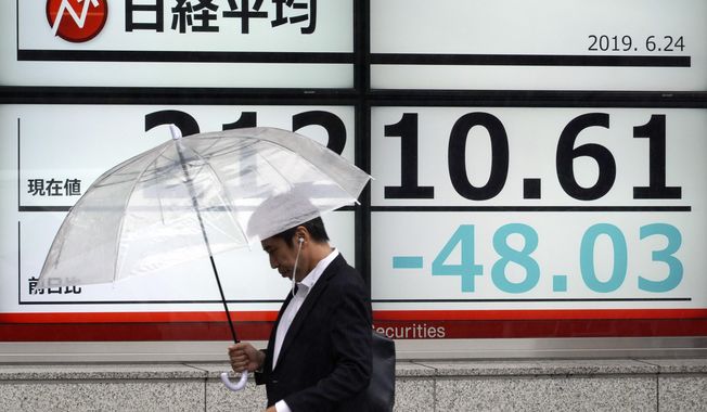 A man walks past an electronic stock board showing Japan&#x27;s Nikkei 225 index at a securities firm in Tokyo Monday, June 24, 2019. Shares were wavering in Asia on Monday as investors watched for movement in the China-U.S. trade dispute ahead of a meeting between Presidents Donald Trump and Xi Jinping planned for later this week in Osaka, Japan, at the Group of 20 summit. (AP Photo/Eugene Hoshiko)