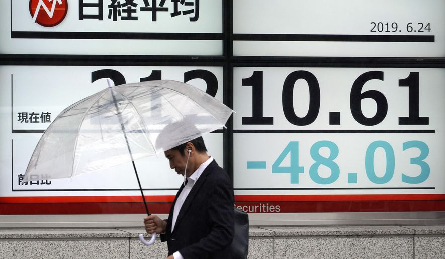 A man walks past an electronic stock board showing Japan&#39;s Nikkei 225 index at a securities firm in Tokyo Monday, June 24, 2019. Shares were wavering in Asia on Monday as investors watched for movement in the China-U.S. trade dispute ahead of a meeting between Presidents Donald Trump and Xi Jinping planned for later this week in Osaka, Japan, at the Group of 20 summit. (AP Photo/Eugene Hoshiko)