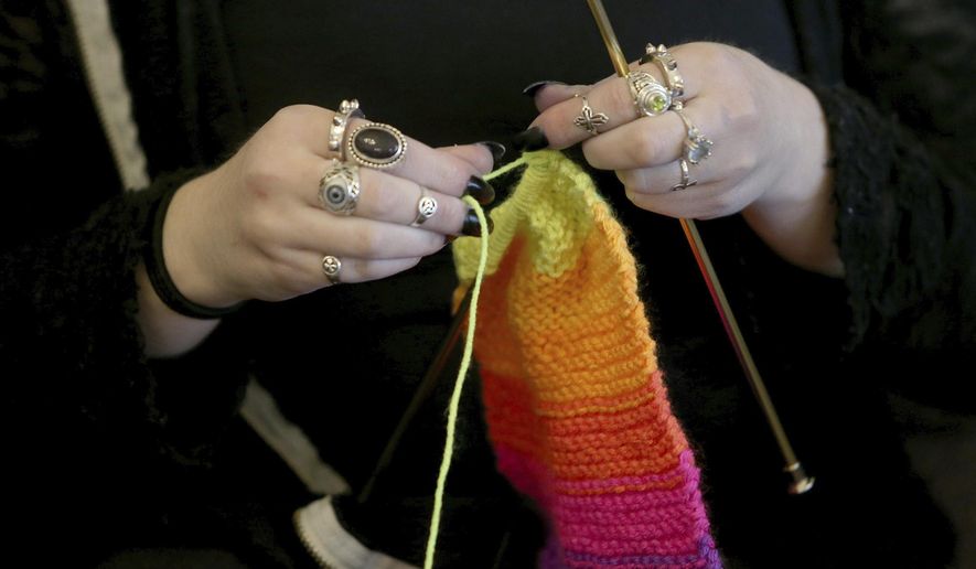FILE - This April 30, 2018 file photo shows a woman knitting in Silverdale Wash. A free, 8-million strong social network for knitters, crocheters and others in the fiber arts has banned any talk of President Donald Trump and his administration. The new policy on Ravelry.com was posted Sunday, June 23, 2019. The post says the site took the action because it can’t provide a space “inclusive of all and also allow support for open white supremacy.” (Larry Steagall/Kitsap Sun via AP, File)