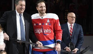 FILE - In this Jan. 18, 2019, file photo, Washington Capitals defenseman Brooks Orpik, center, poses with Dick Patrick, left, team president, and Bill Daly, deputy NHL commissioner, after he was given a silver stick during a ceremony to honor Opik for playing 1,000 NHL hockey games, before the team&#39;s matchup against the New York Islanders in Washington. Orpik has decided to retire after 15 seasons and two Stanley Cup championships. The 38-year-old announced his retirement Tuesday, June 25, 2019. Orpik says his body is “telling me it is time to move on to something new” after 1,171 NHL regular-season and playoff games.  (AP Photo/Nick Wass, File)