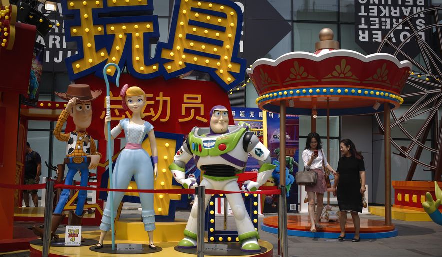 A woman browses her photo after taking with her friend near the American latest animated film "Toy Story 4" promotion decoration on display at the capital city's popular shopping mall in Beijing, Tuesday, June 25, 2019. China says its trade negotiators are talking to their U.S. counterparts on how to resolve disputes ahead of an expected meeting between their two heads of state at the G20 meeting in Japan later this week. (AP Photo/Andy Wong)