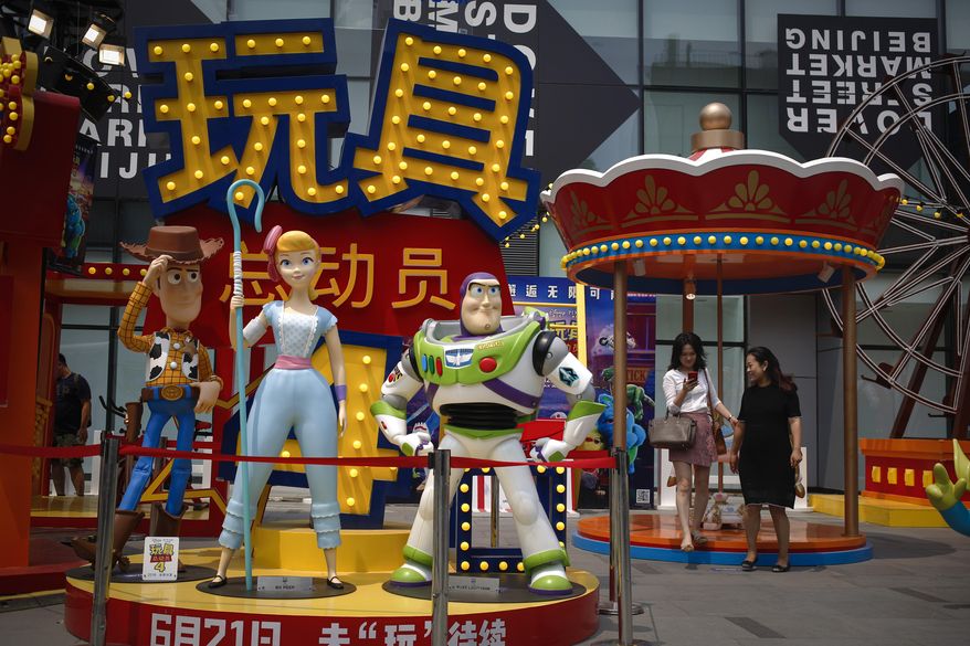 A woman browses her photo after taking with her friend near the American latest animated film "Toy Story 4" promotion decoration on display at the capital city's popular shopping mall in Beijing, Tuesday, June 25, 2019. China says its trade negotiators are talking to their U.S. counterparts on how to resolve disputes ahead of an expected meeting between their two heads of state at the G20 meeting in Japan later this week. (AP Photo/Andy Wong)