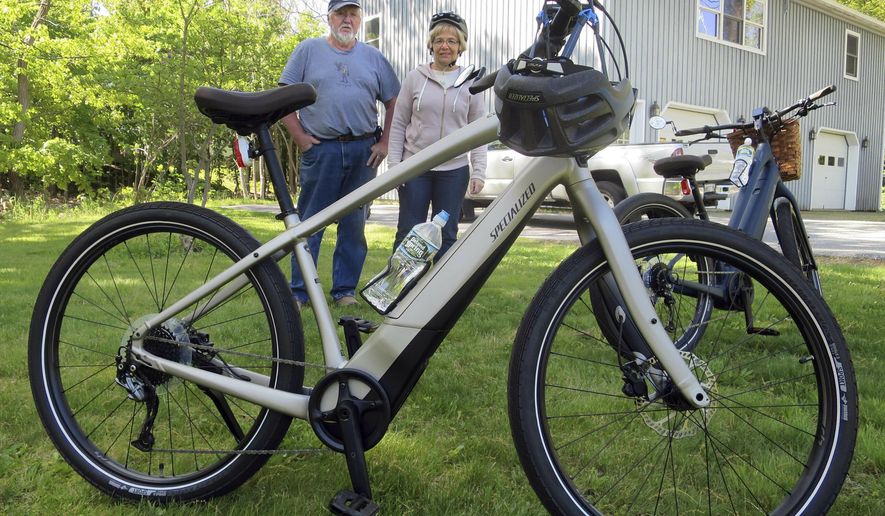In this June 8, 2019 photo, Gordon and Janice Goodwin show their electric-assist bicycles outside their home in Bar Harbor, Maine. The bikes are banned on carriage roads and bicycle paths in nearby Acadia National Park. (AP Photo/David Sharp)