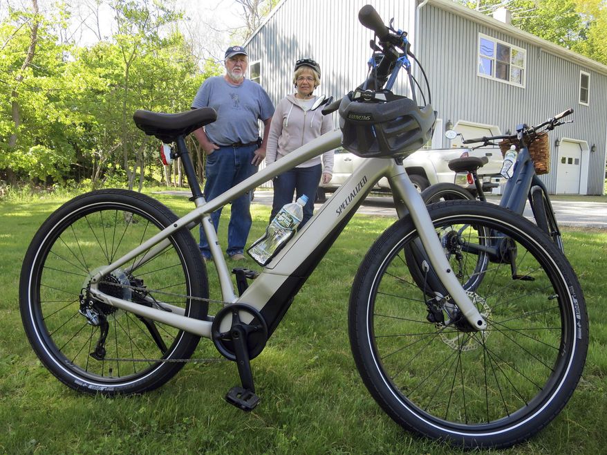 In this June 8, 2019 photo, Gordon and Janice Goodwin show their electric-assist bicycles outside their home in Bar Harbor, Maine. The bikes are banned on carriage roads and bicycle paths in nearby Acadia National Park. (AP Photo/David Sharp)